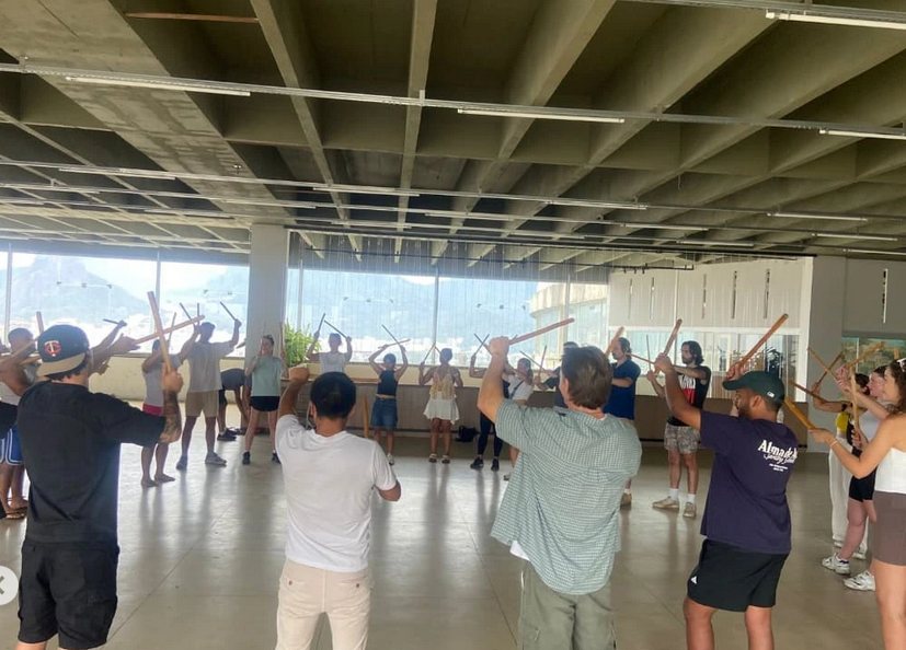 Aula coletiva de berimbau com dezenas de alunos