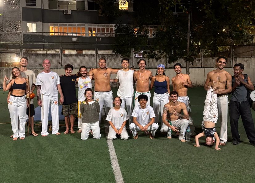 Grupo de alunos da Capoeira Liberdade reunido no campo à noite