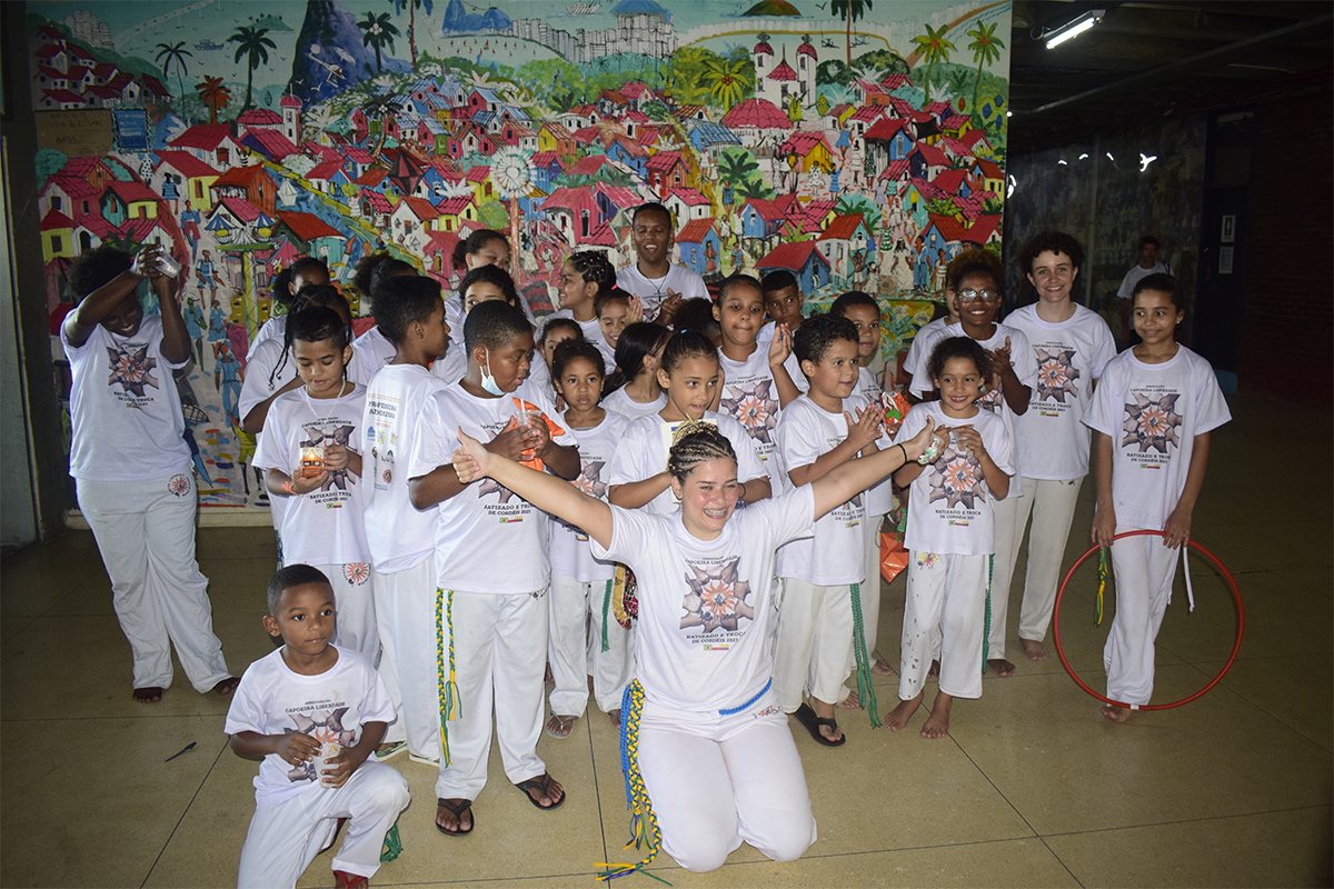 Turma infantil de capoeira posando diante de um mural colorido